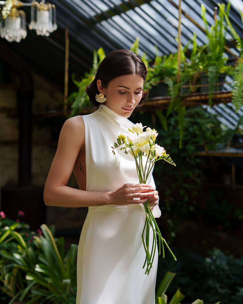 Woman in a white dress holding flowers in a garden setting