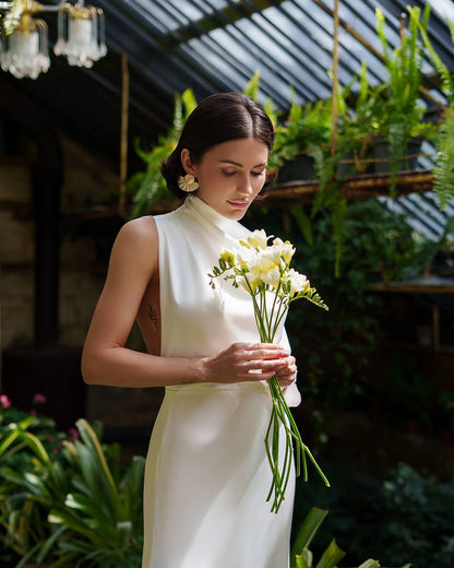 Woman in a white dress holding flowers in a garden setting