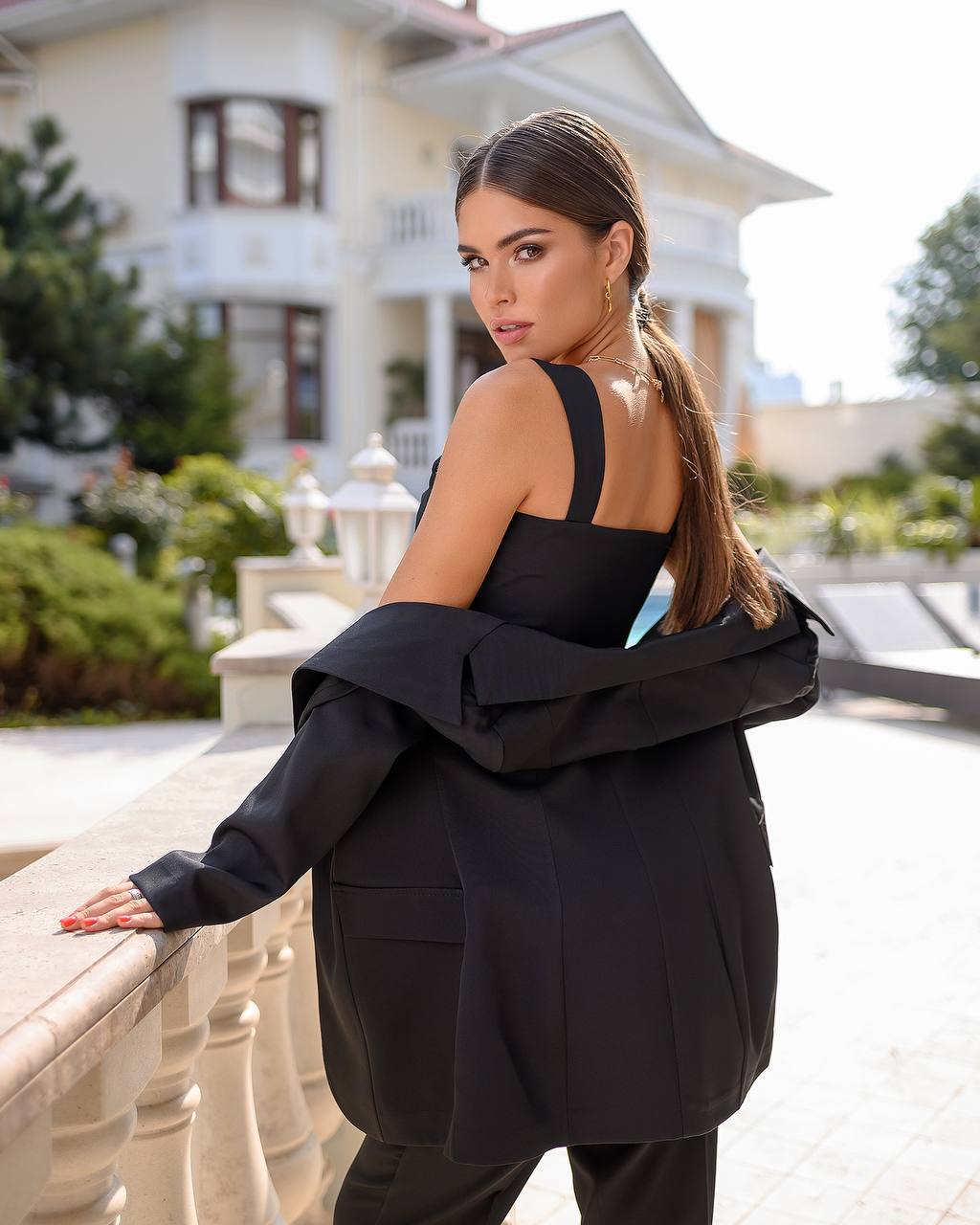 Woman in a black outfit standing outdoors with a building in the background