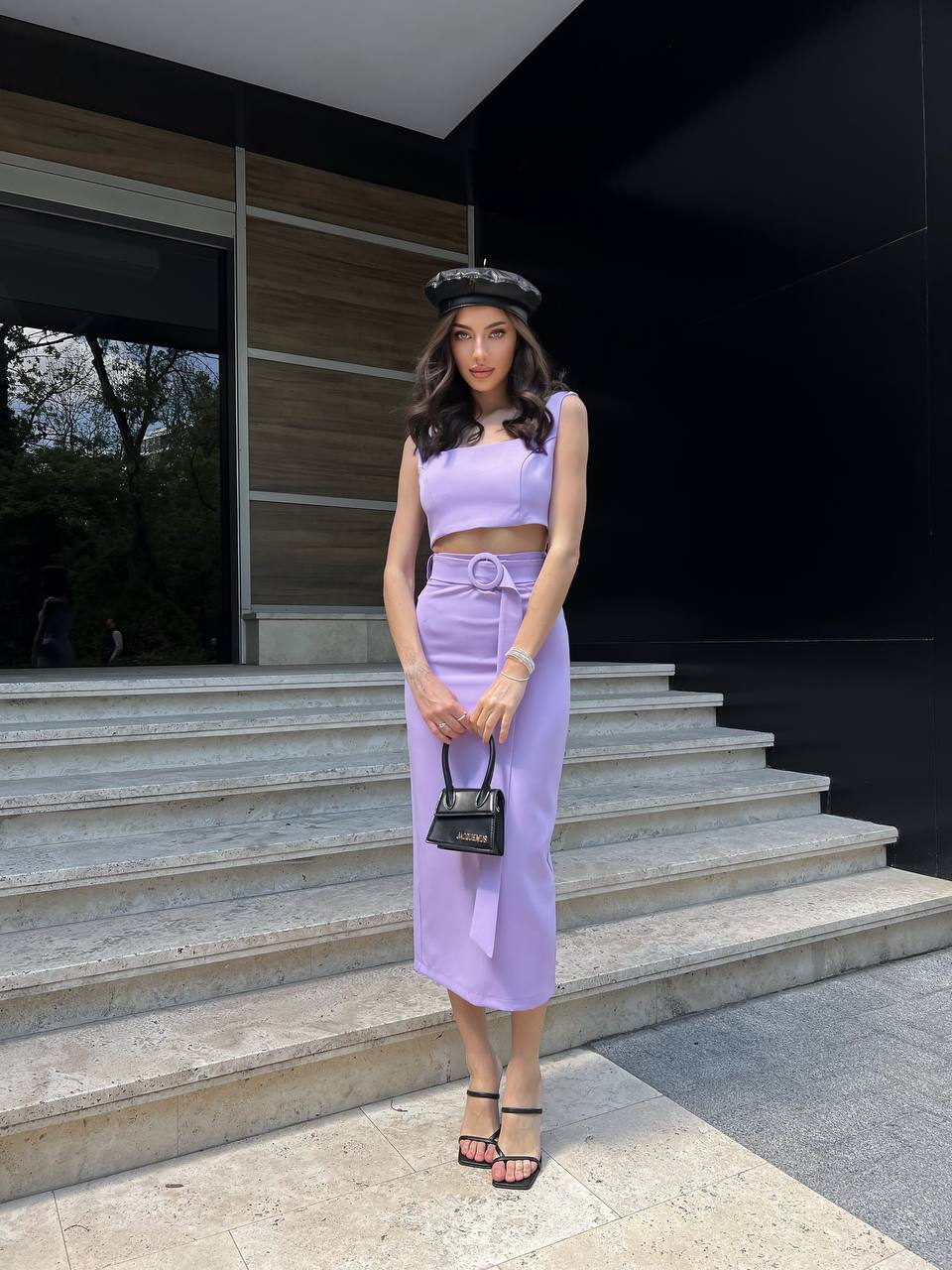 Woman in a lavender outfit standing on steps outside a modern building