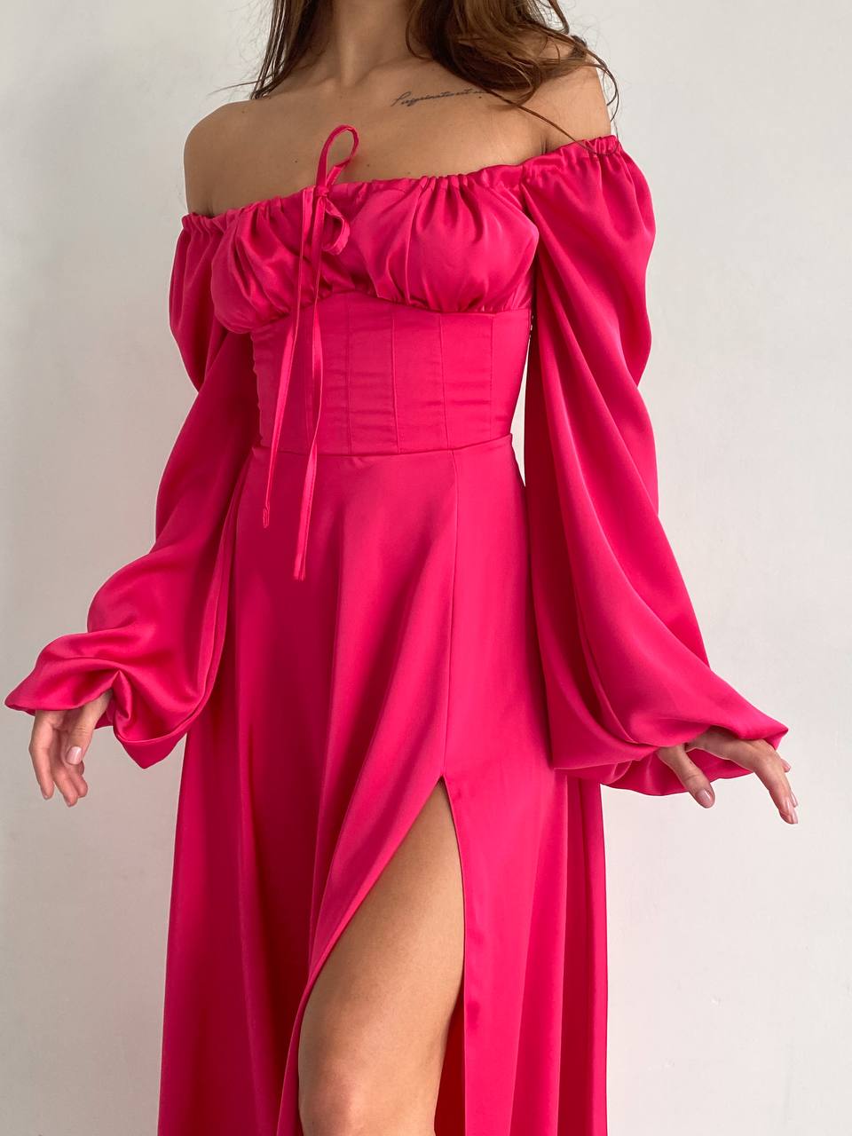 Pink off-shoulder dress with long sleeves on a plain background