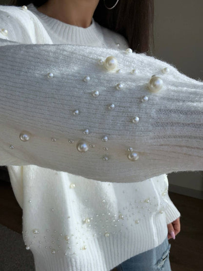 White sweater with pearl embellishments worn by a person.