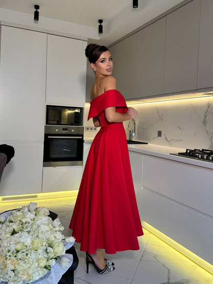 Woman in a red off-shoulder dress standing in a modern kitchen.