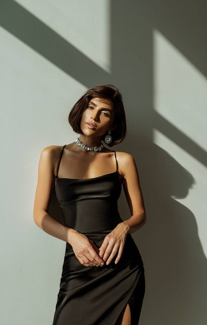 Woman in a black dress standing against a wall with shadows
