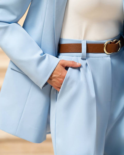 Light blue suit with a brown belt and gold buckle on a neutral background