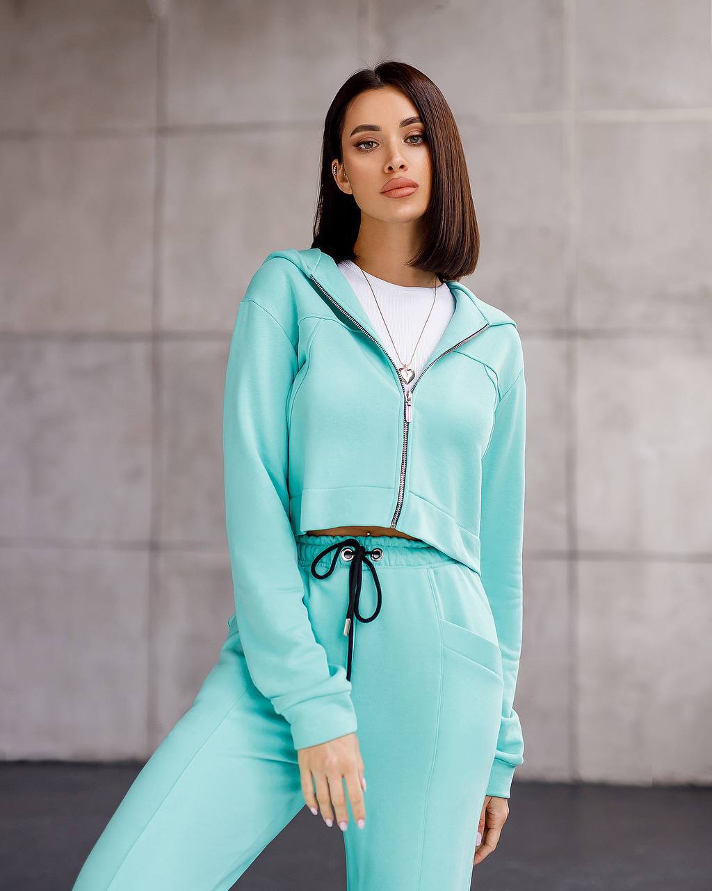Woman wearing a turquoise tracksuit against a neutral background
