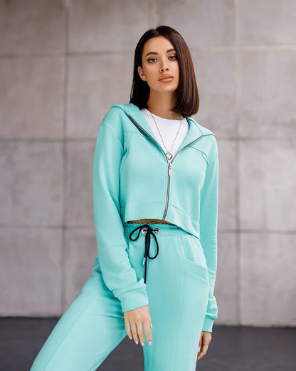 Woman wearing a turquoise tracksuit against a neutral background