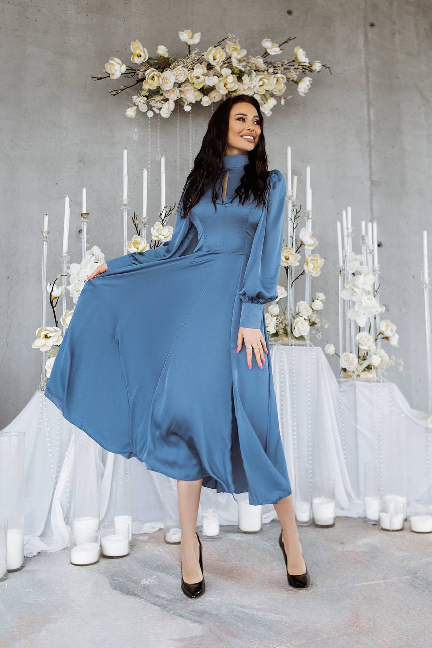 Woman in a blue dress posing in a decorated room with white flowers and candles.