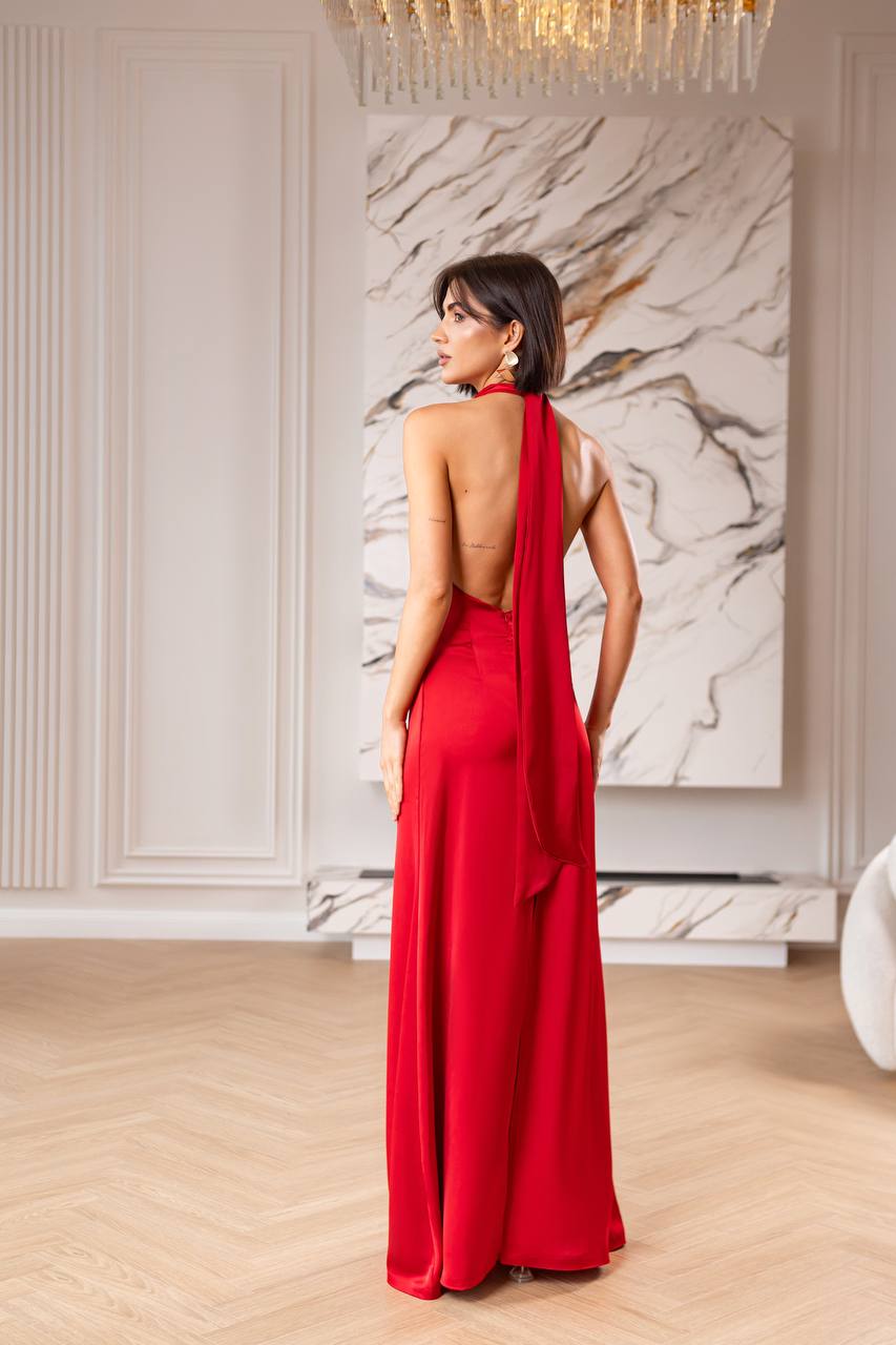 Woman in a red evening gown standing in a stylish room with marble wall art.