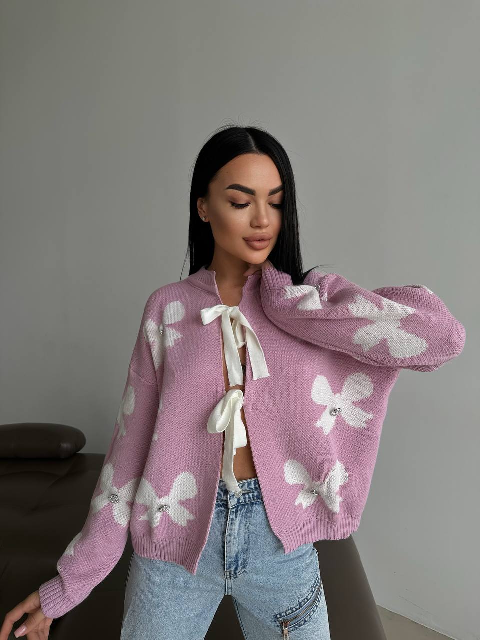 Woman wearing a pink cardigan with white butterfly patterns against a neutral background