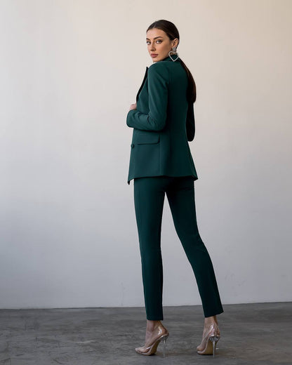 Woman wearing a green suit standing against a plain background