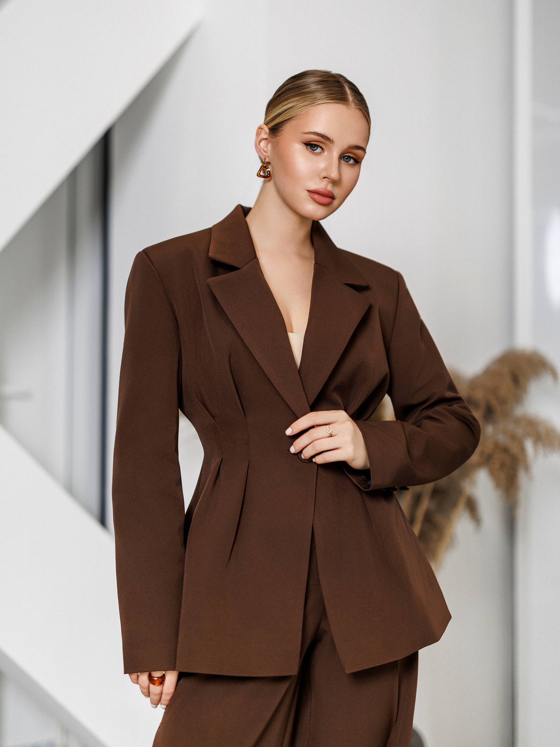 Woman wearing a brown suit against a neutral background