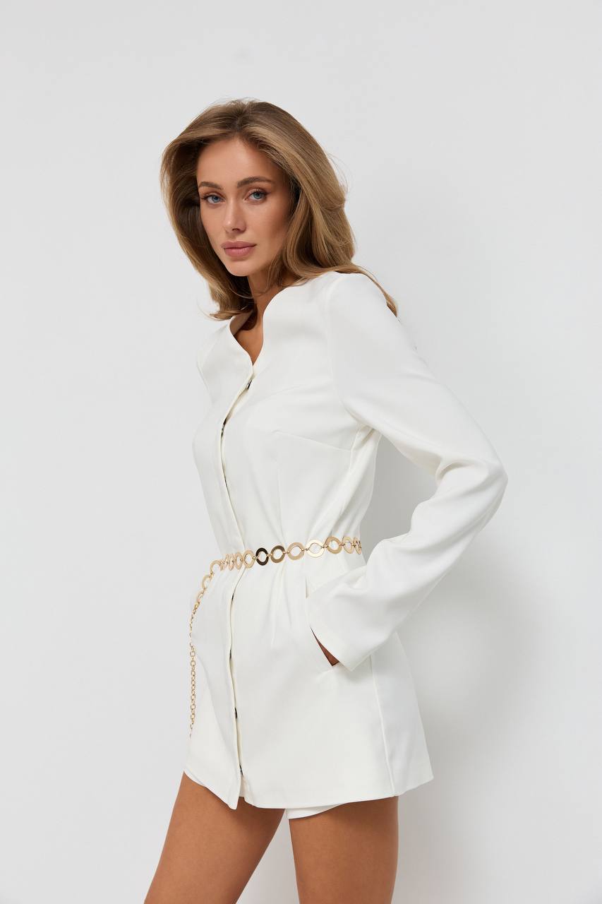 Woman wearing a white blazer dress with a gold belt on a white background