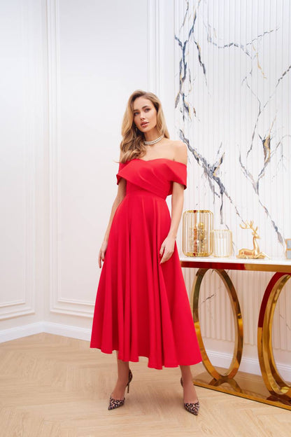 Woman in a red off-shoulder dress standing in an elegant room with marble walls.