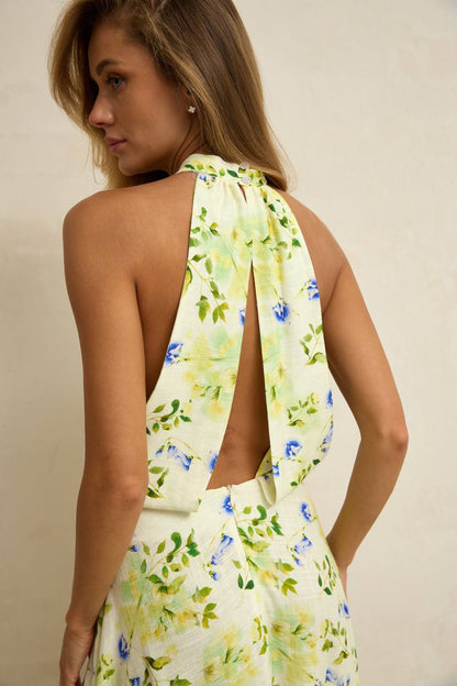 Woman wearing a floral dress with a halter neck design on a plain background