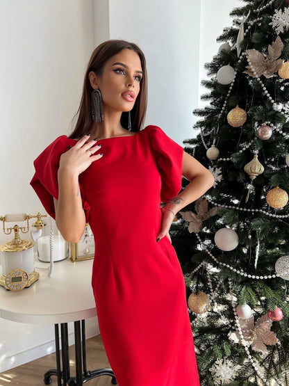 Woman in a red dress standing next to a decorated Christmas tree.
