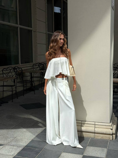 Woman in a white outfit standing outdoors near a building.