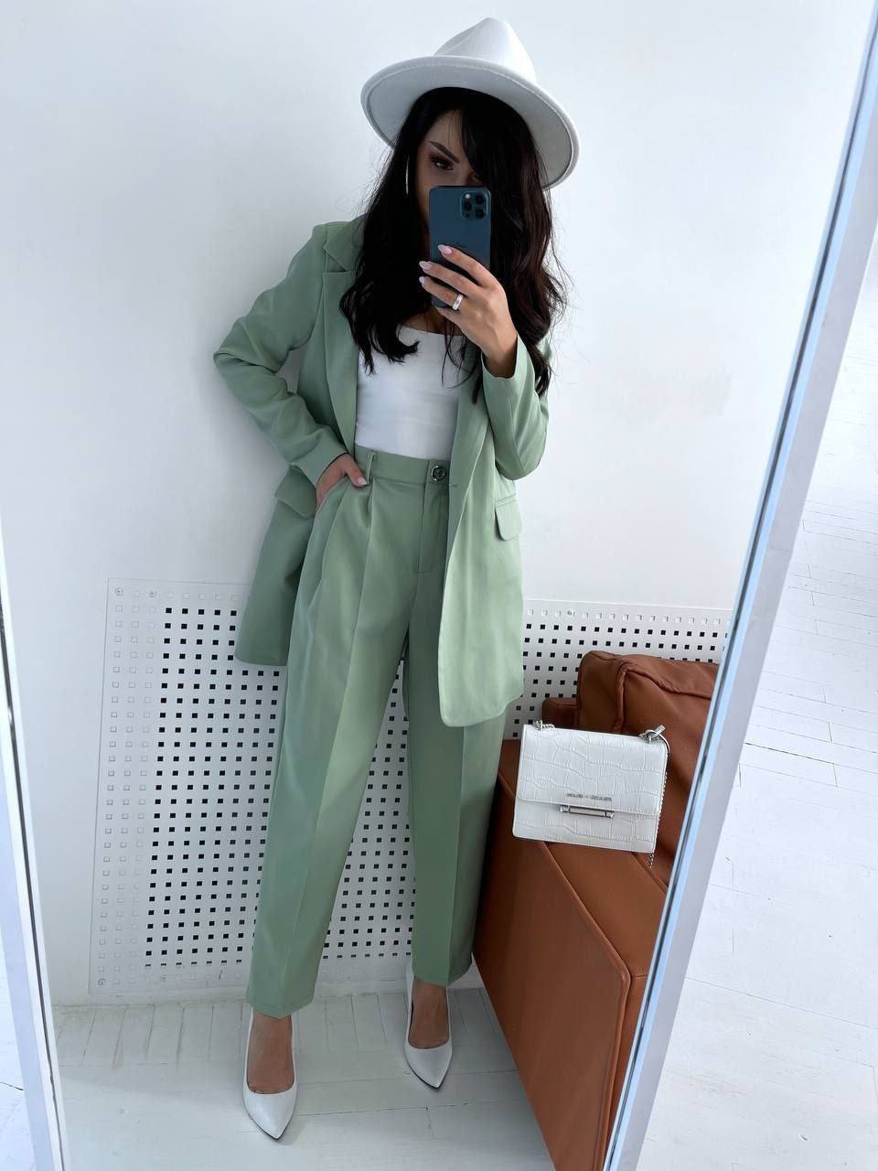 Person wearing a light green suit with a white hat and shoes, standing in front of a mirror.