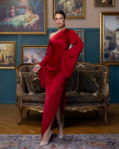 Woman in a red dress standing in an elegant room with classical paintings on the wall.