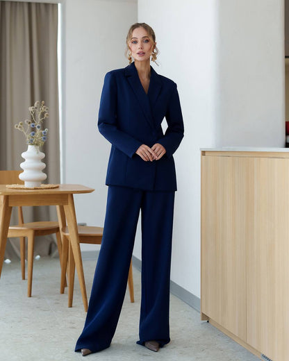 Woman in a navy blue suit standing in a modern interior setting.