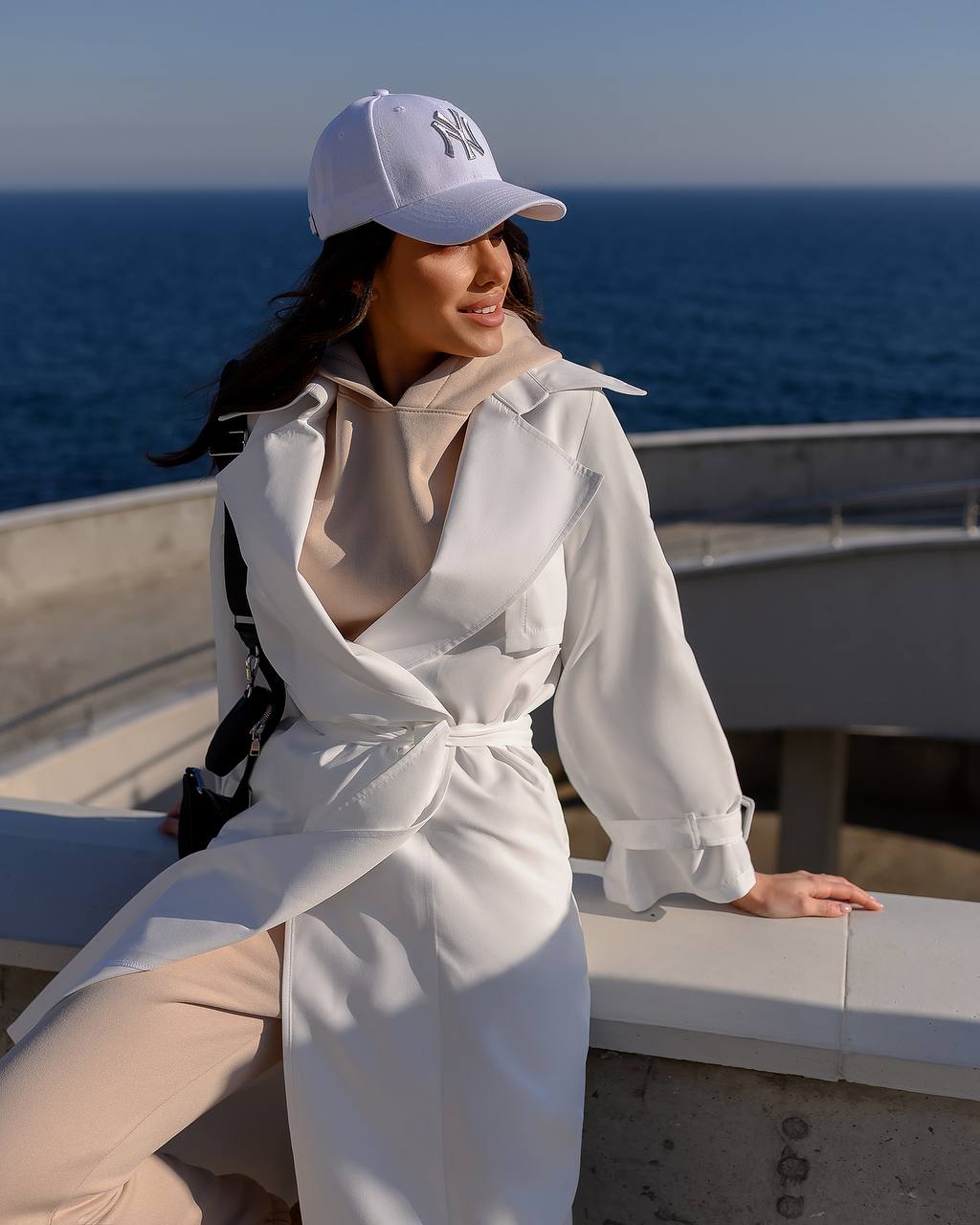 Woman in a white coat and cap standing on a boat with ocean in the background