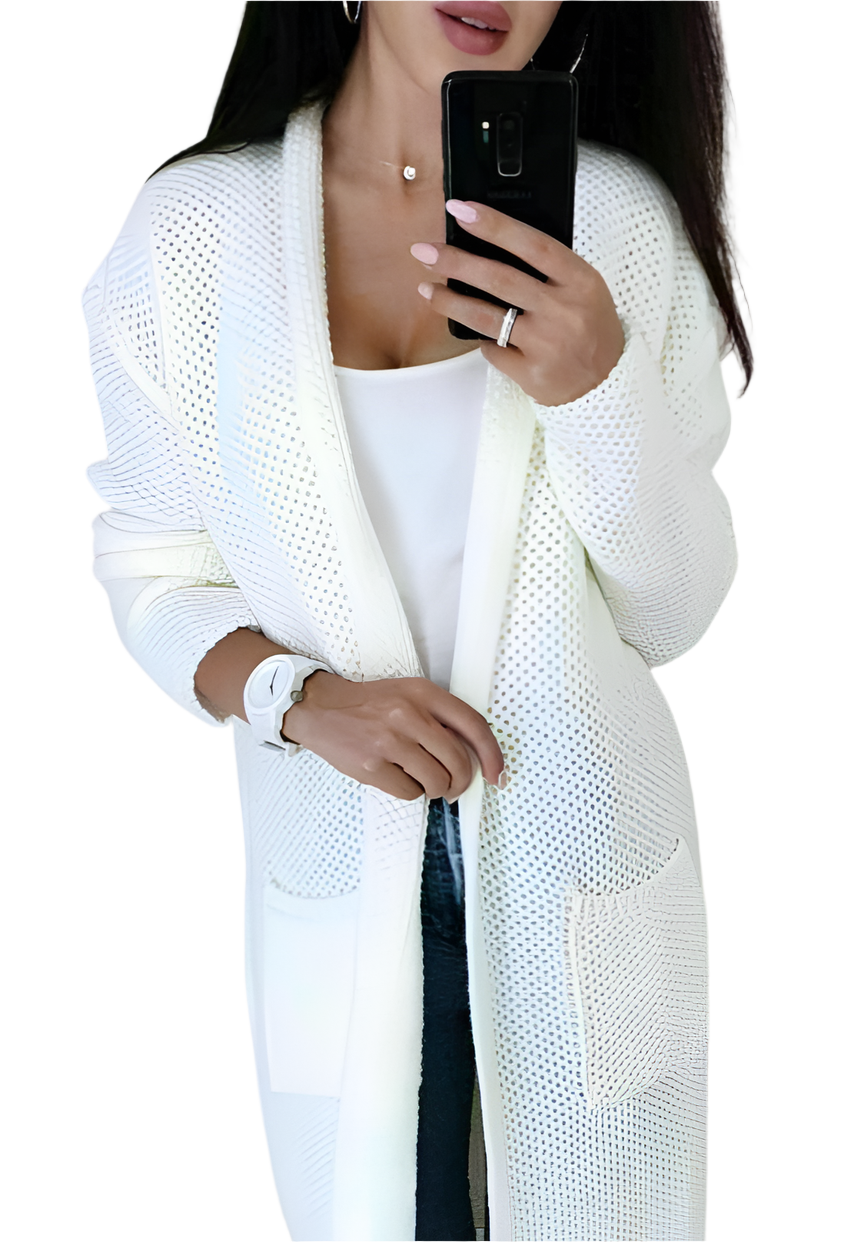 Woman wearing a white knit cardigan over a white top, holding a phone.