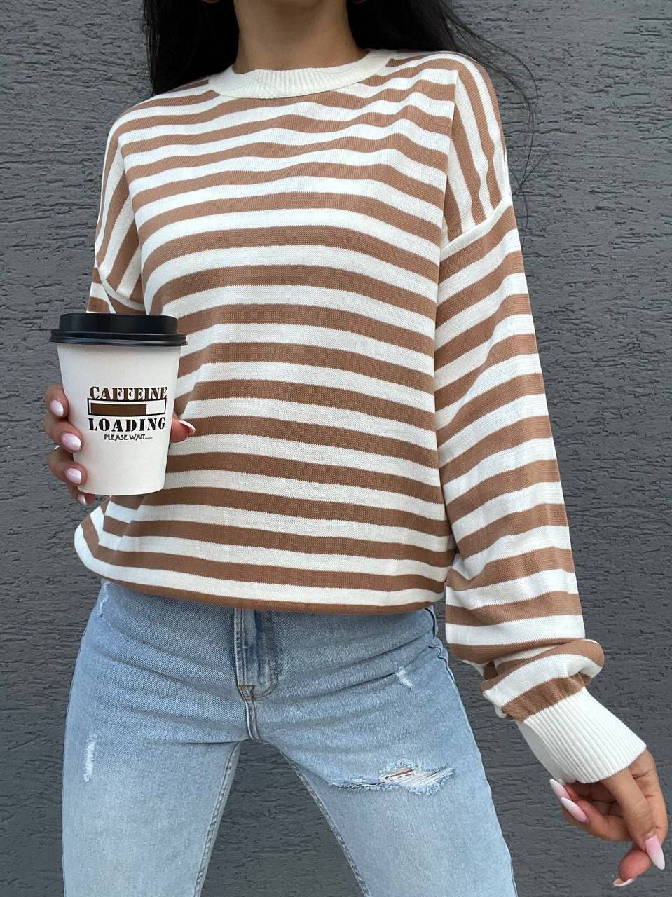 Person wearing a brown and white striped sweater holding a coffee cup with 'Caffeine Loading' text.