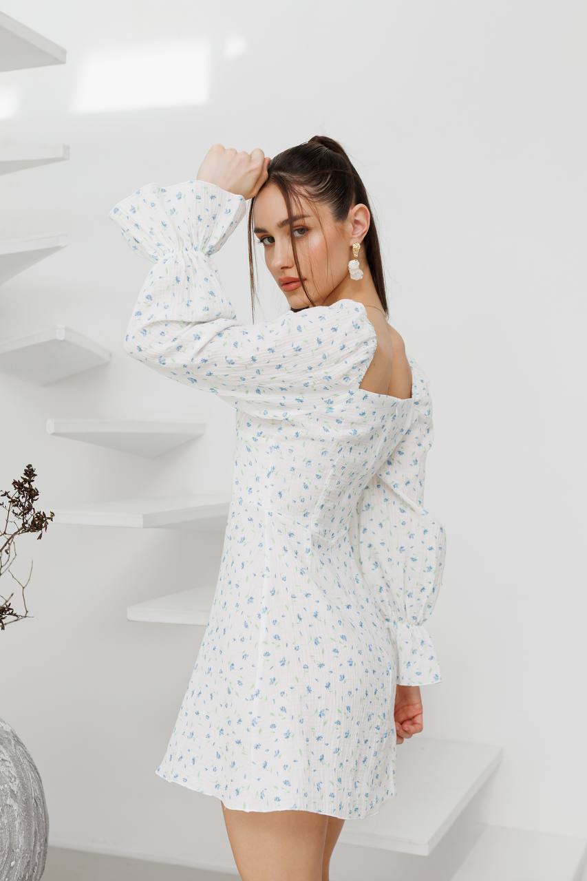 Woman wearing a white floral dress in a minimalistic setting