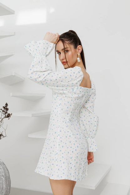 Woman wearing a white floral dress in a minimalistic setting