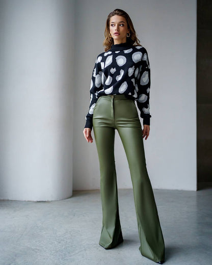 Woman wearing a patterned sweater and green pants against a neutral background