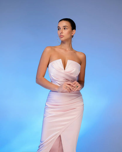 Woman wearing a strapless pink gown against a blue background