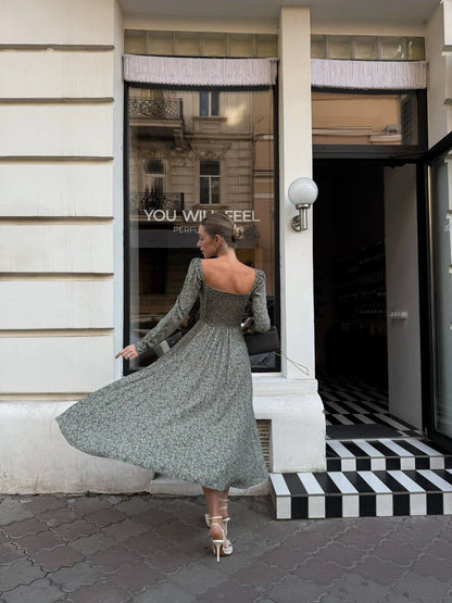 Woman in a gray dress standing in front of a store entrance.