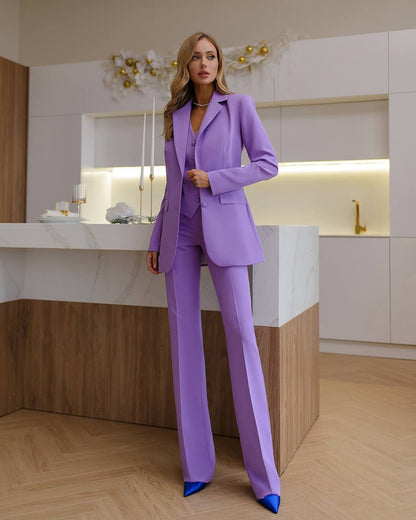 Woman in a purple suit standing in a modern kitchen.