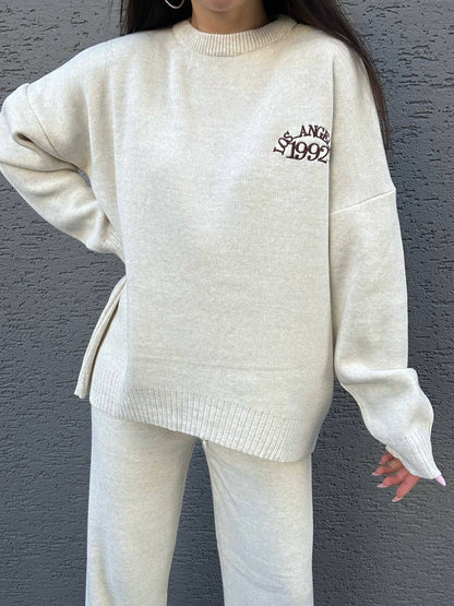 Person wearing a cream-colored sweater with text on it against a gray background