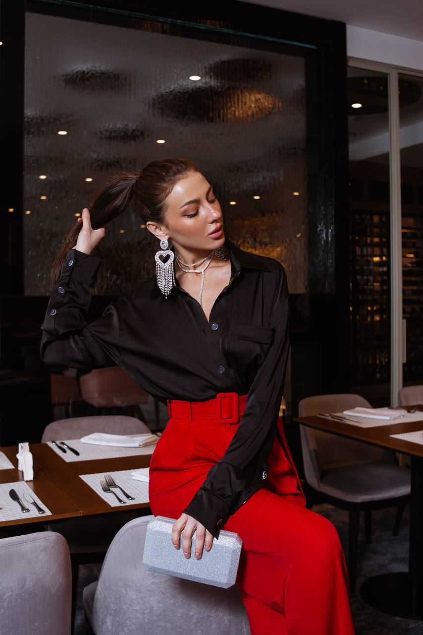 Woman in a black shirt and red pants sitting at a restaurant table.
