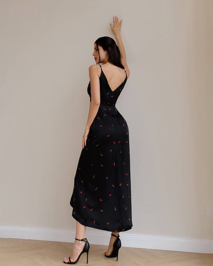 Woman wearing a black dress with a subtle pattern, standing against a plain wall.