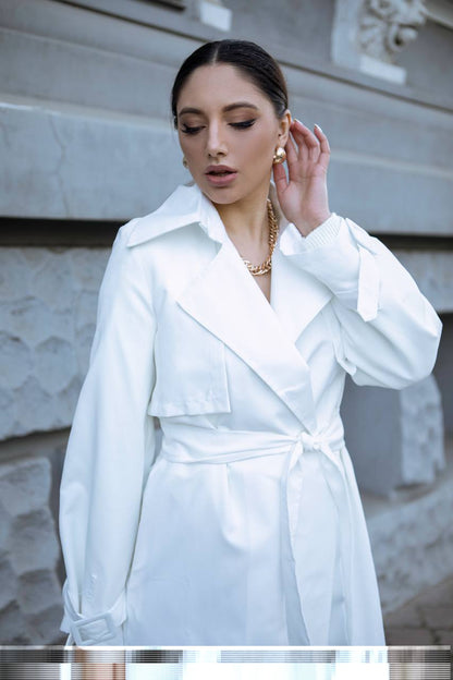 Woman wearing a white coat in front of a marble wall