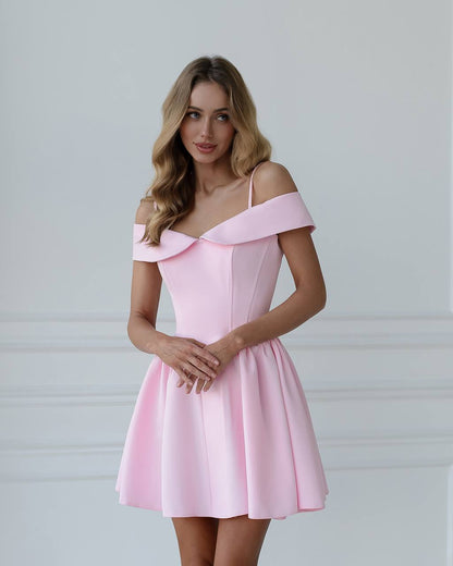 Woman wearing a pink off-shoulder dress against a plain background