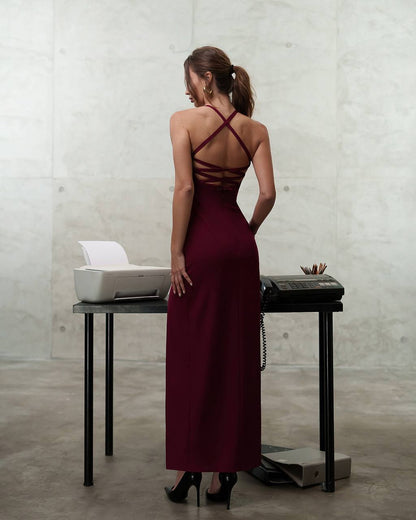 Woman in a burgundy dress standing in front of a desk with office equipment.