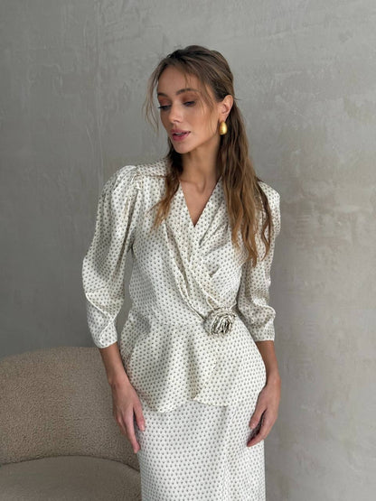 Woman wearing a white polka dot dress against a gray wall