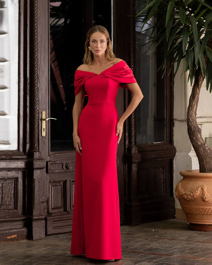 Woman in a red evening gown standing in an elegant indoor setting.