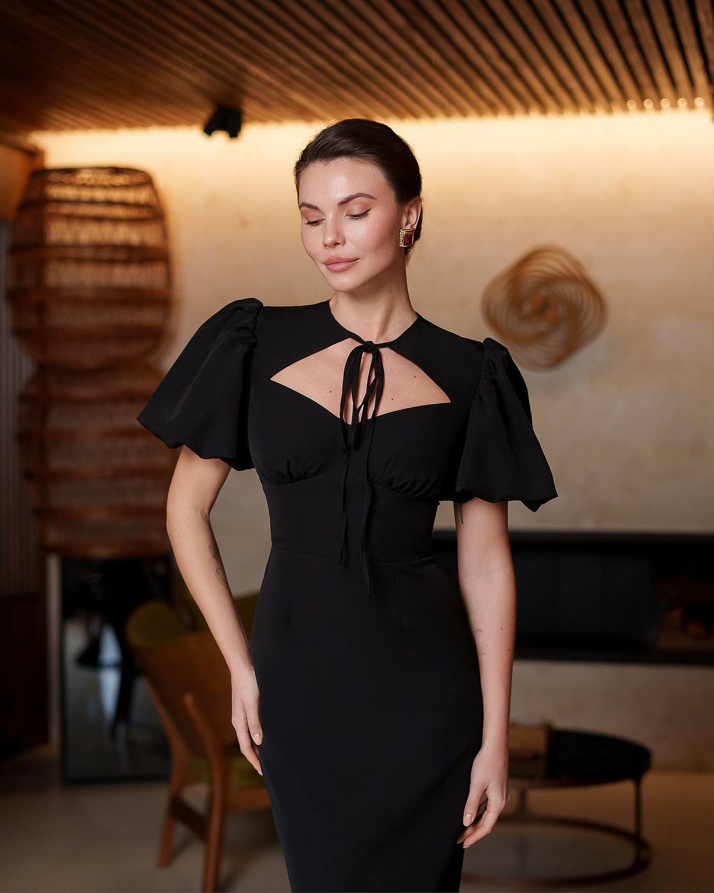 Woman wearing a black dress with ruffled sleeves in an indoor setting