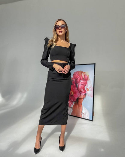 Woman in black outfit standing in front of a floral artwork on a gray background