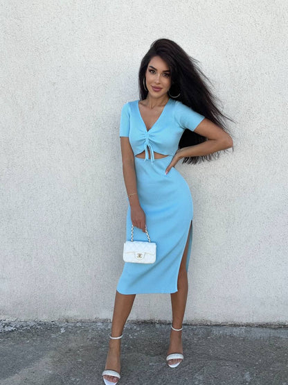 Woman wearing a light blue dress with a white handbag against a plain background
