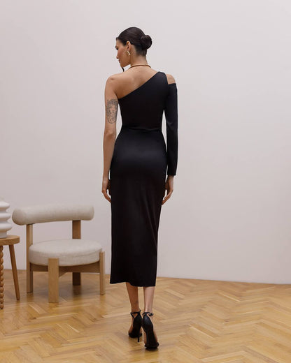 Woman wearing a black one-shoulder dress in an indoor setting with wooden flooring and a chair.