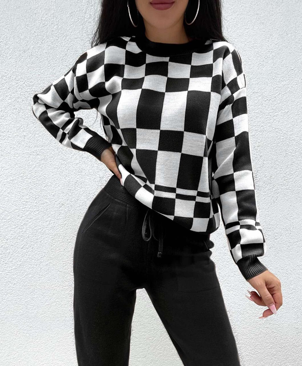 Person wearing a black and white checkered sweater against a light gray background