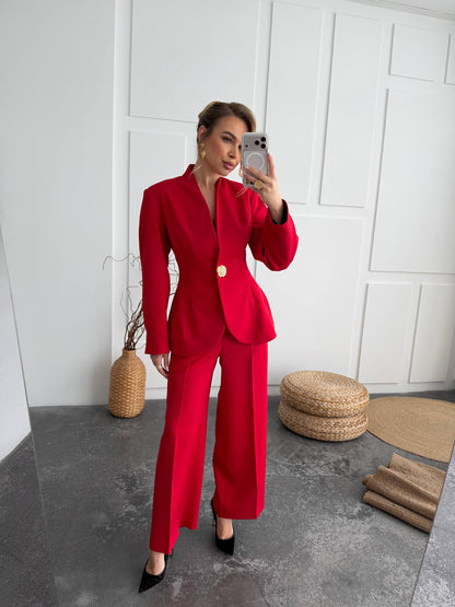 Person wearing a red suit taking a mirror selfie in a minimalistic room.