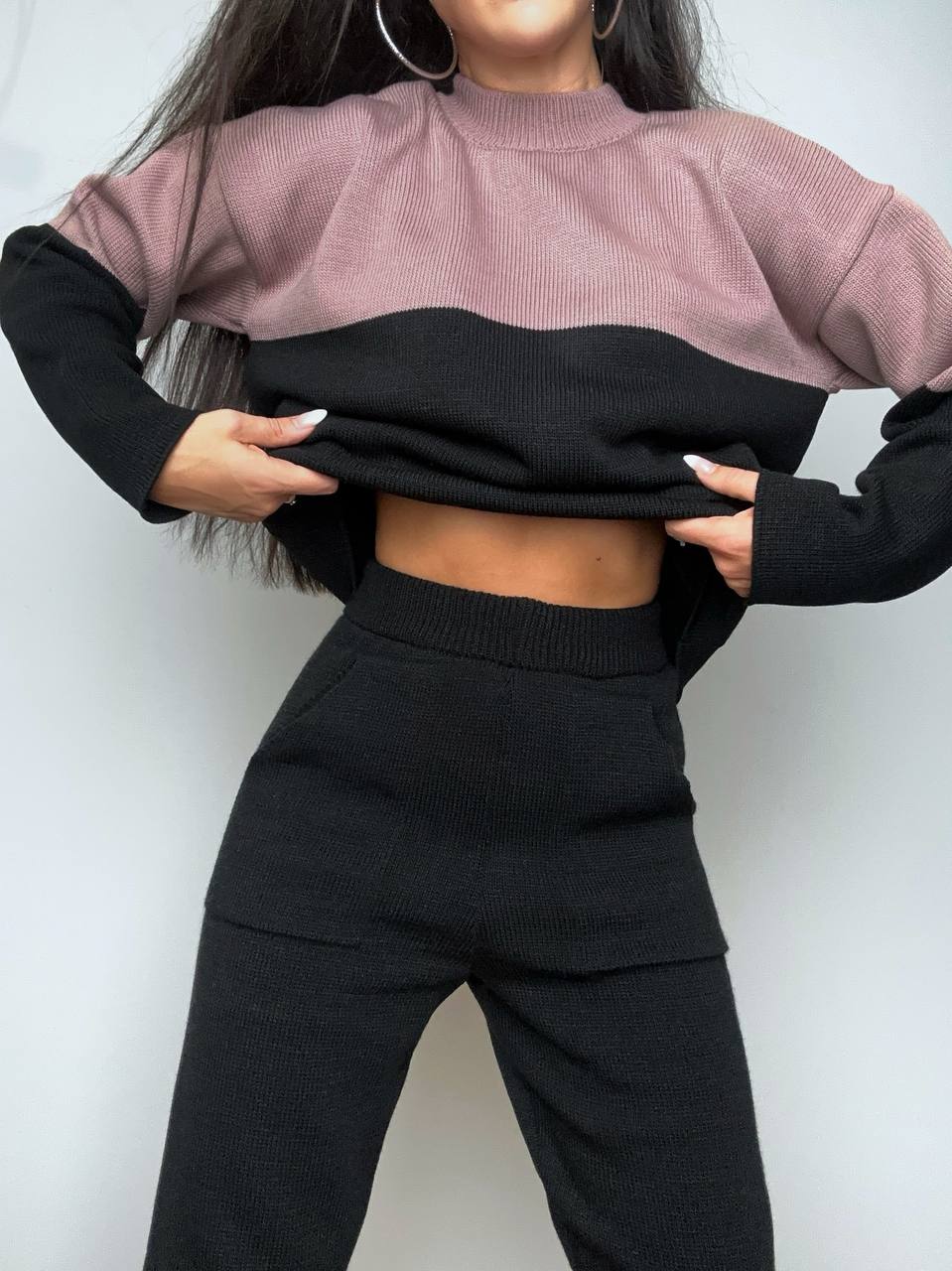 Person wearing a two-tone sweater with black and pink colors on a plain background