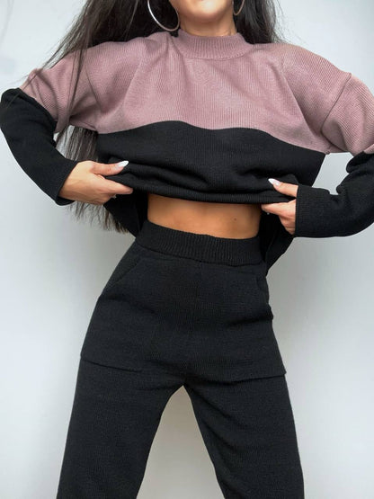 Person wearing a two-tone sweater with black and pink colors on a plain background