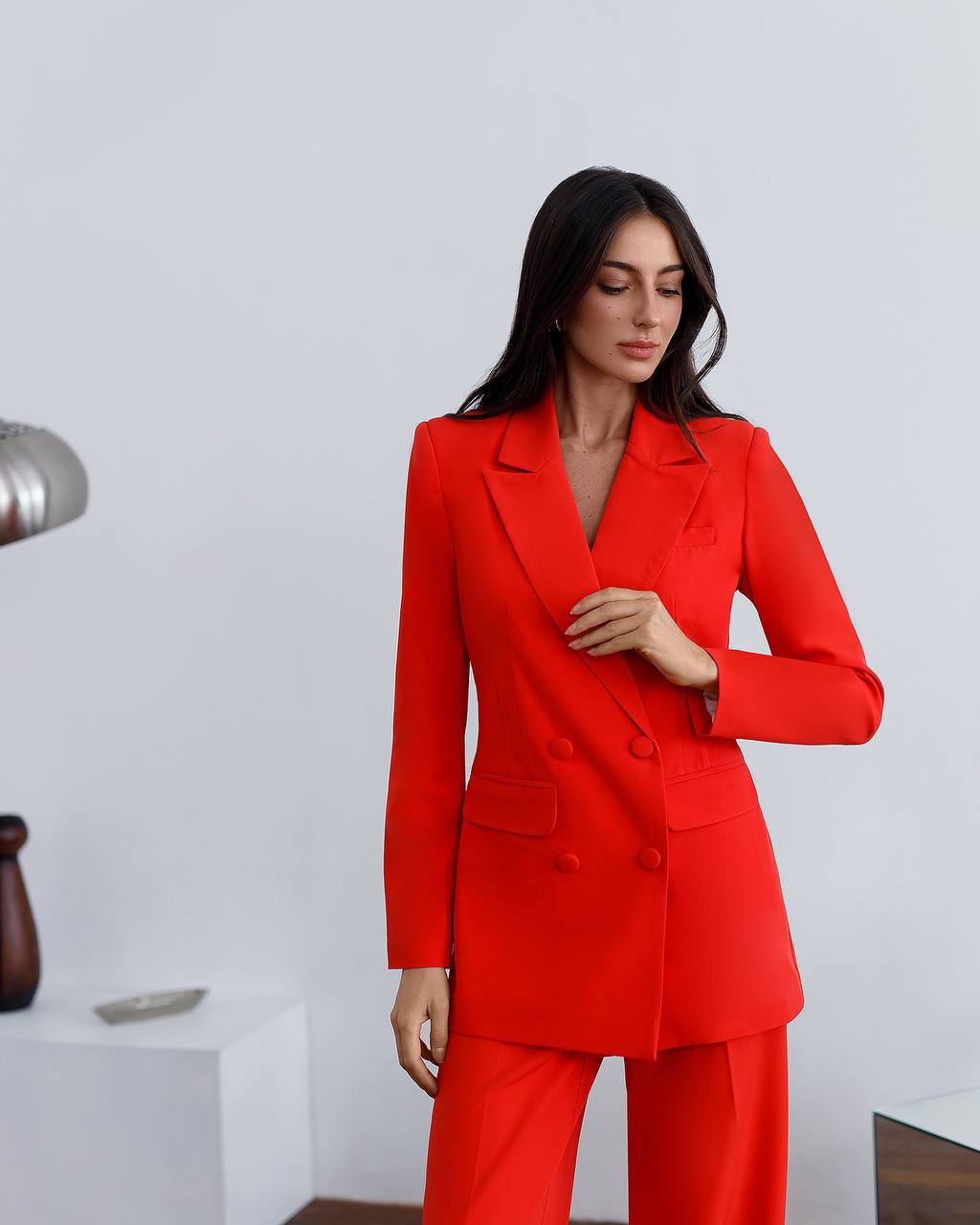 Woman wearing a red suit in a minimalistic room.